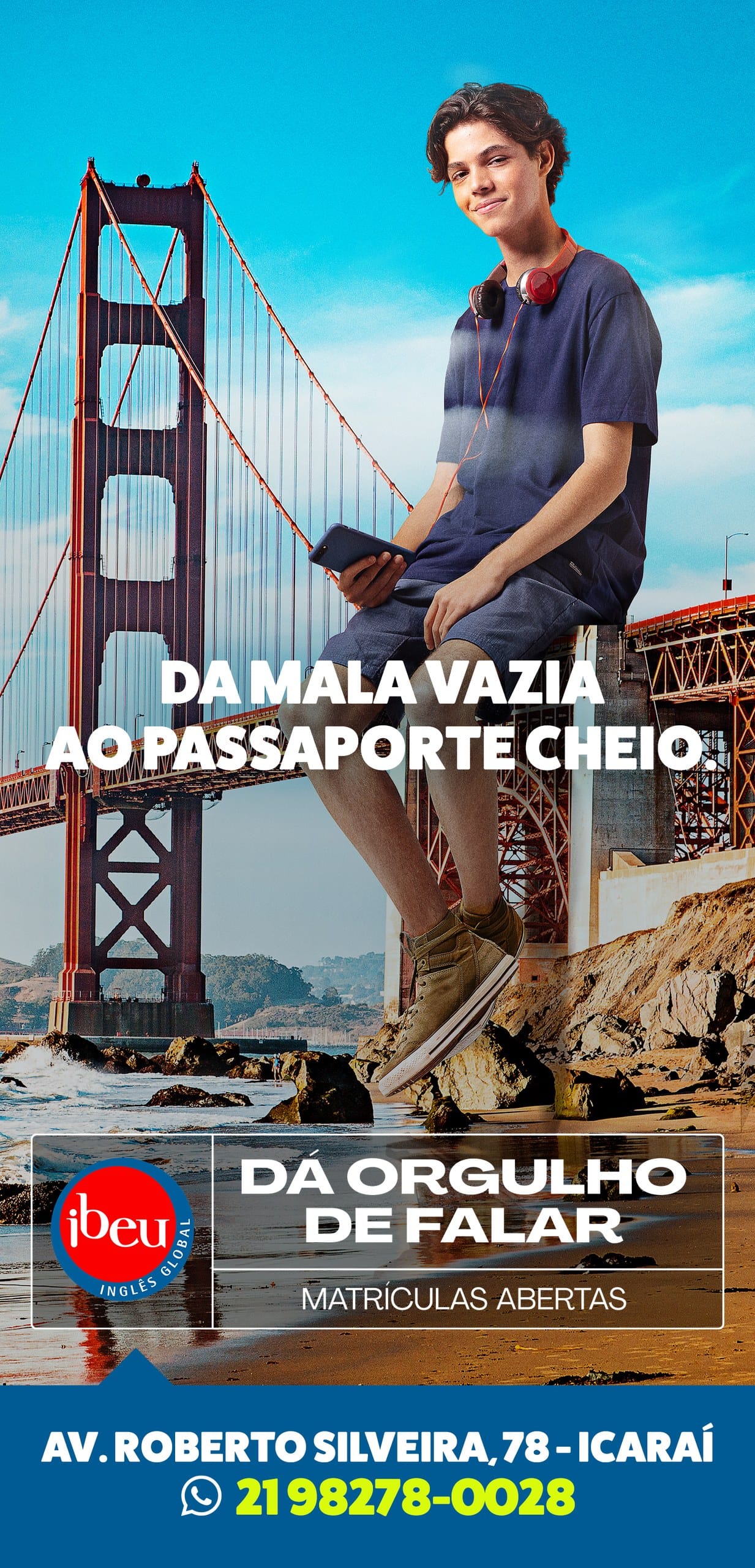 Empena vertical do Ibeu: um jovem de fone no pescoço sentado sobre a Golden Gate, com a frase Da mala vazia ao passaporte cheio e a assinatura Dá orgulho de falar