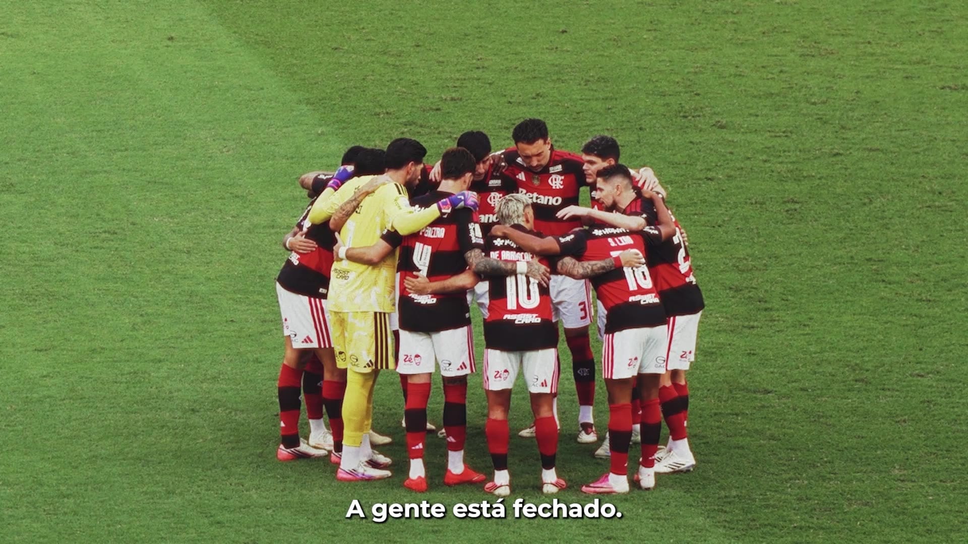 Jogadores do Flamengo reunidos em círculo no gramado, com a frase: a gente está fechado