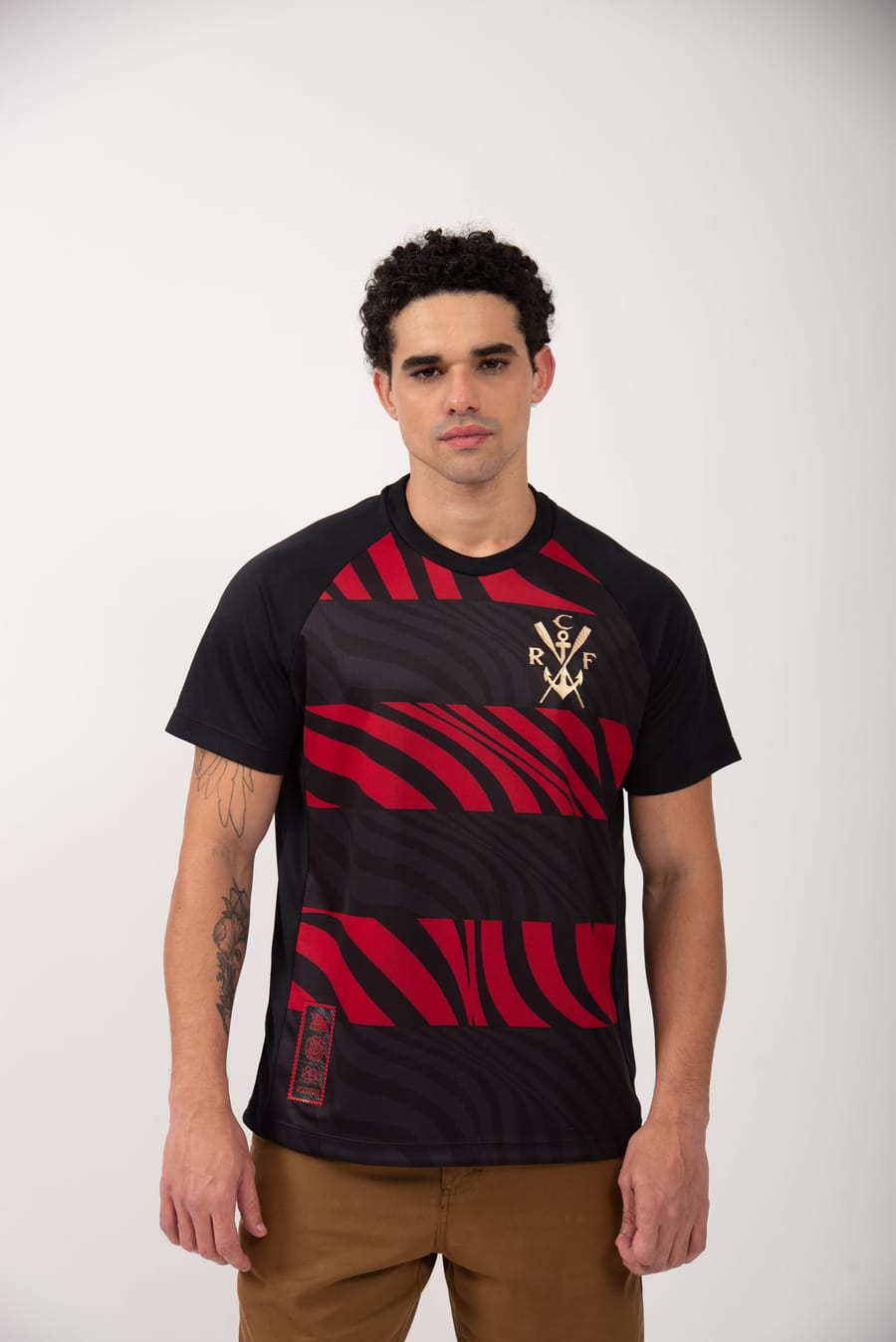 Modelo veste a camisa Pherusa, com a gola e o escudo do Flamengo em destaque, sobre fundo claro