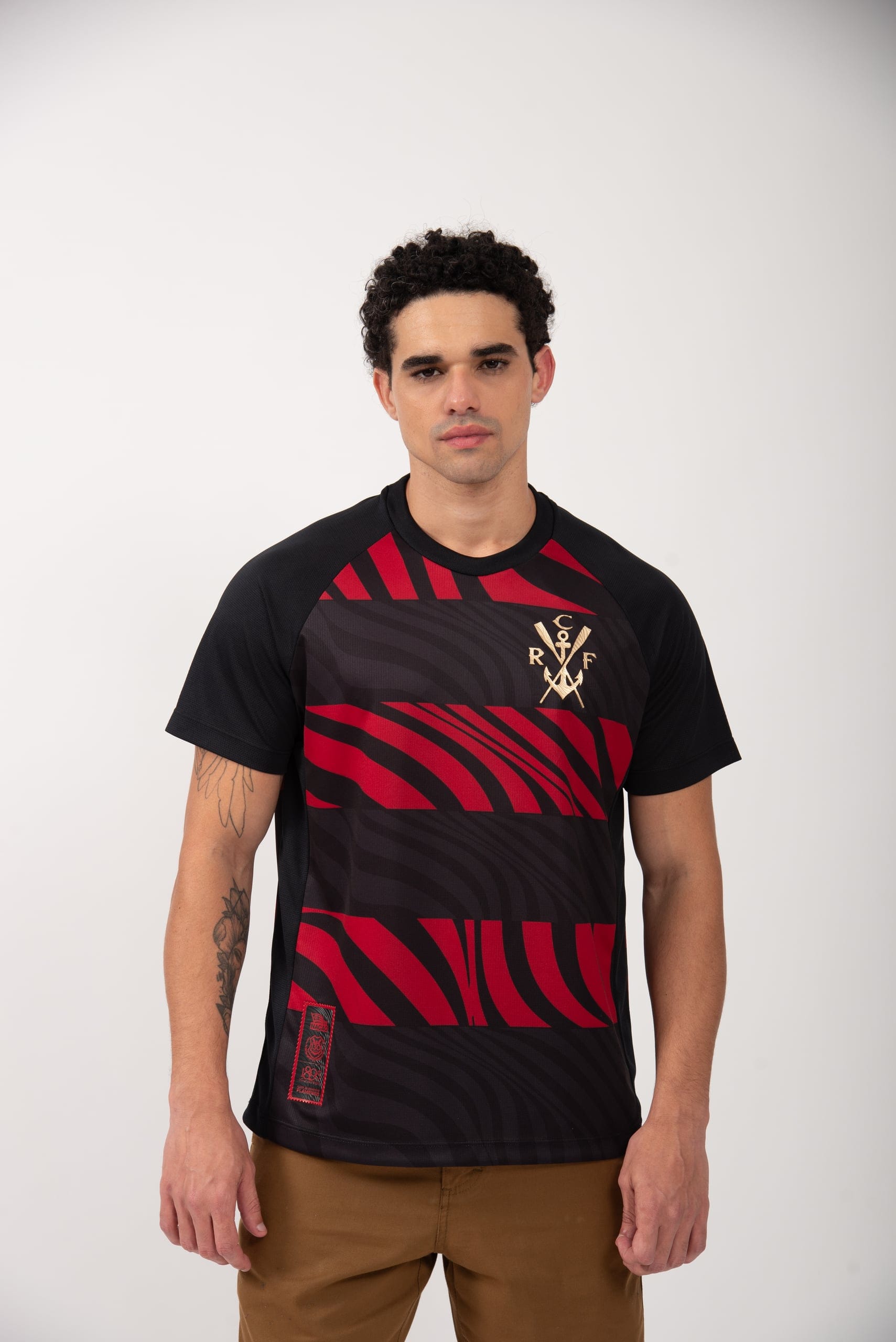 Modelo veste a camisa Pherusa, com a gola e o escudo do Flamengo em destaque, sobre fundo claro